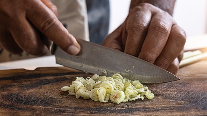 A chef slicing lemongrass, showing the claw grip. 