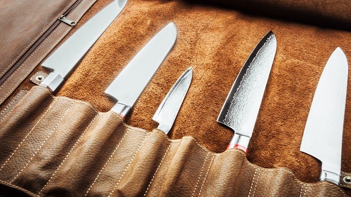 A set of professional knives stored in a leather case. 