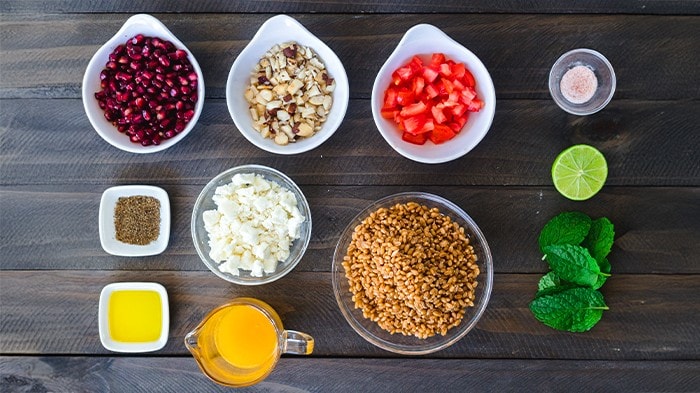 Mise en place of salad ingredients in small bowls on a wooden table.