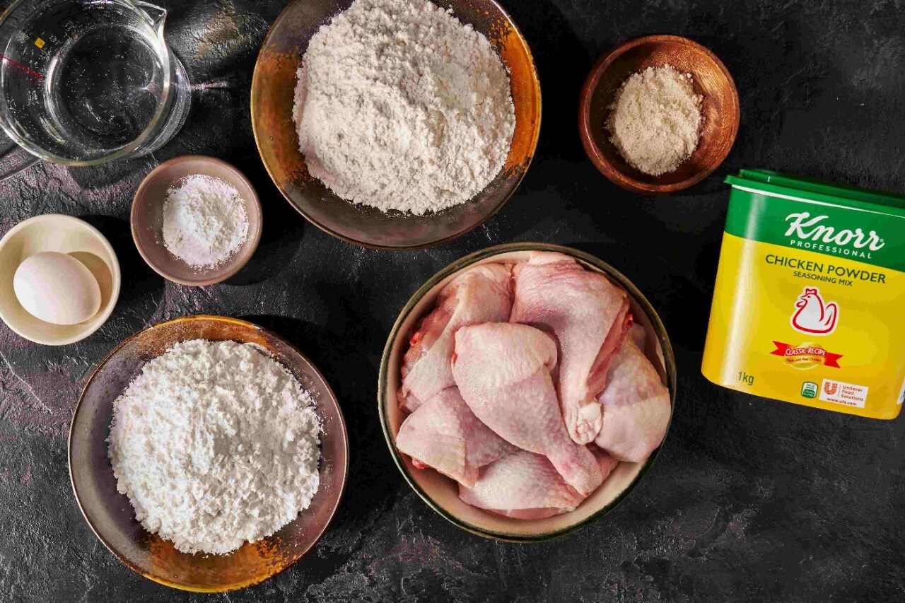 Ingredients for fried chicken laid on a black tabletop Ingredients for fried chicken laid on a black tabletop