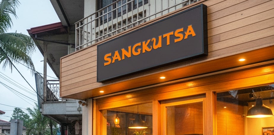 Café signage with black background hanging on wood fence.