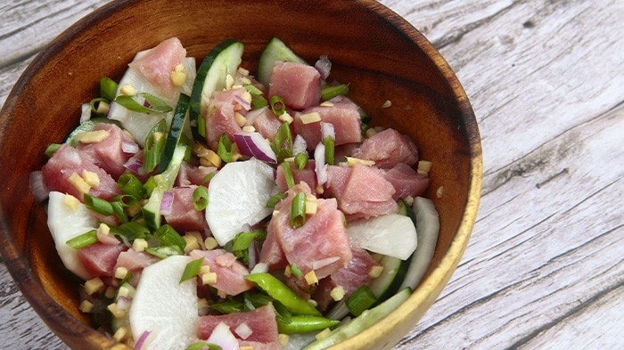 Fresh tuna kinilaw with cucumber in a wooden bowl.