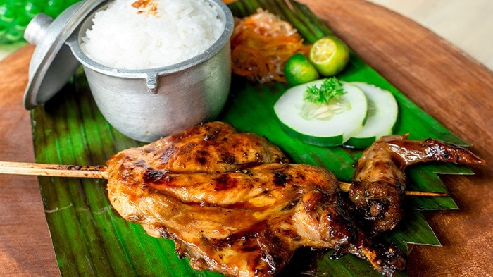 Chicken into on a stick with white rice, atchara, and vegetables.