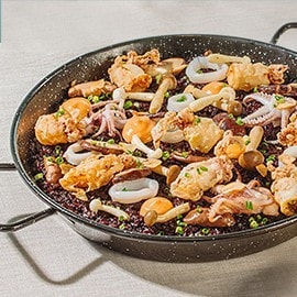 Black paella topped with crispy squid, adobong pusit, and pickled mushrooms. Black paella topped with crispy squid, adobong pusit, and pickled mushrooms.