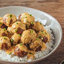 Embutido meatballs topped with cheese sauce over rice. Embutido meatballs topped with cheese sauce over rice.