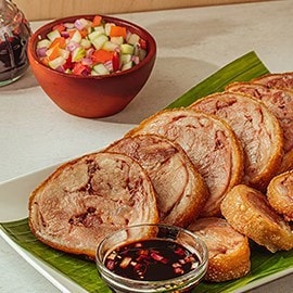 Boneless crispy pata on a white platter with ensalada and vinegar. Boneless crispy pata on a white platter with ensalada and vinegar.