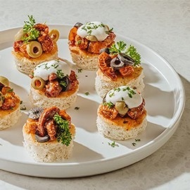 Pork adobo on bread rounds garnished with olives and chorizo. Pork adobo on bread rounds garnished with olives and chorizo.