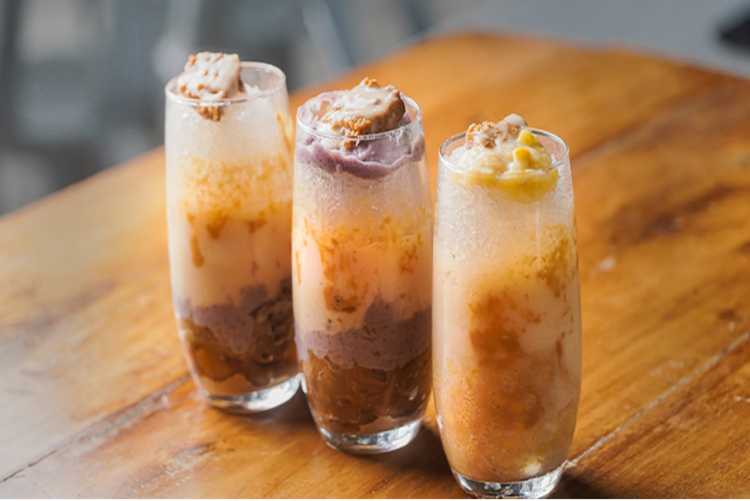 Three glasses of halo-halo on a wooden table. 
