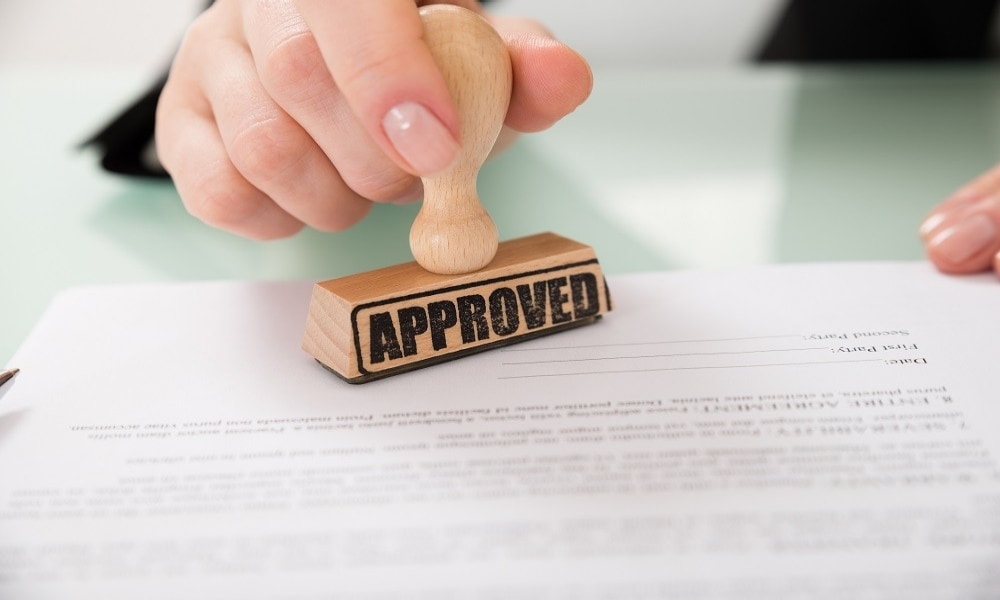 A person approves an application form with a wooden stamp A person approves an application form with a wooden stamp