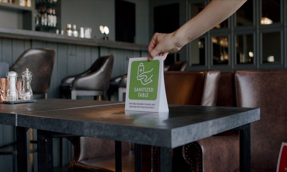 Restaurant staff places sanitation signs on dining tables. Restaurant staff places sanitation signs on dining tables.