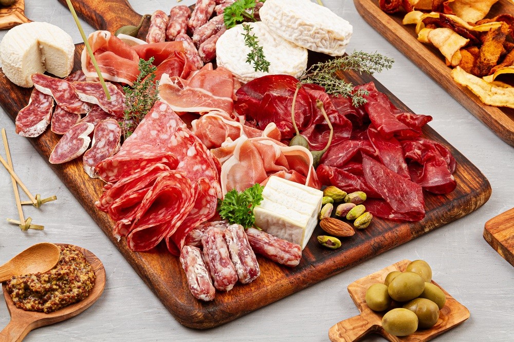 A rustic grazing table of assorted sliced meats, nuts, and cheeses A rustic grazing table of assorted sliced meats, nuts, and cheeses